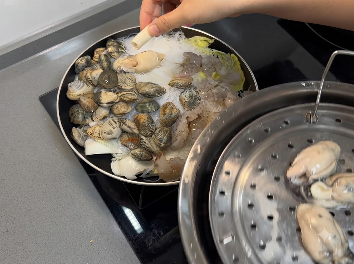 Garnelen und frische Austern werden auf die Meeresfrüchte- und Nudelmischung in der Pfanne gelegt.