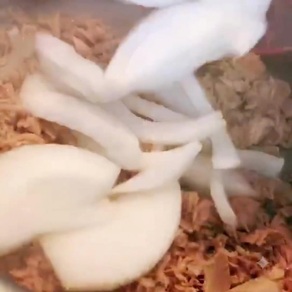 Geschnittene Zwiebeln werden in den Topf mit Thunfisch gegeben und umgerührt.