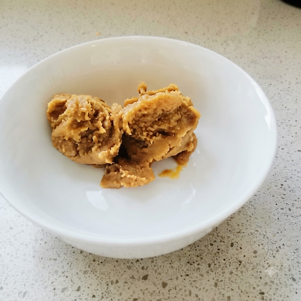 Koreanische Sojabohnenpaste und Chilipaste werden in einer weißen Schüssel mit einem goldenen Löffel gründlich vermischt.