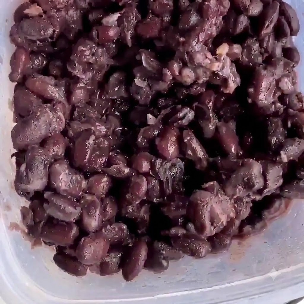 Gekochte schwarze Bohnen in einem Plastikbehälter bereit zum Zerstampfen.
