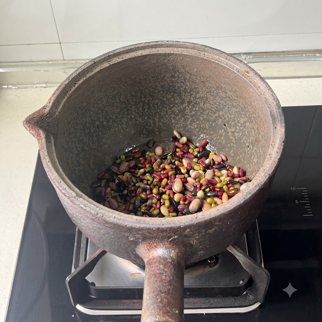 Gemischte Bohnen liegen am Boden eines Steingutkochtopfs, nachdem Wasser hinzugefügt wurde.