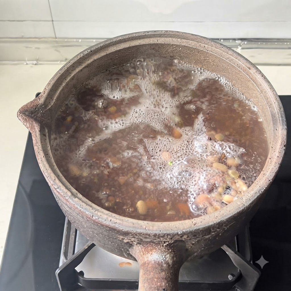 Ein Steinguttopf mit Deckel steht während des Kochvorgangs auf einer modernen Herdplatte.