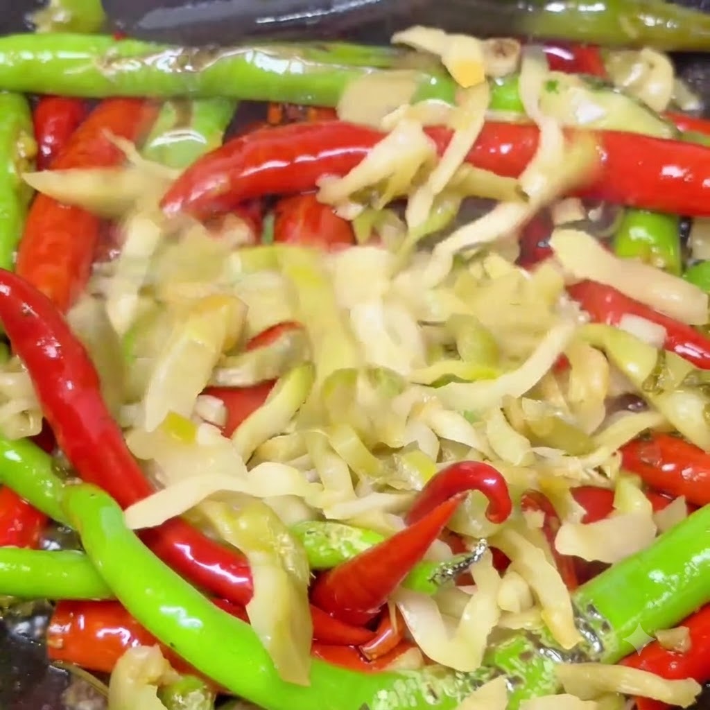 Eingelegter Senfkohl vermischt mit gerösteten Chilis brät in einem heißen Wok.