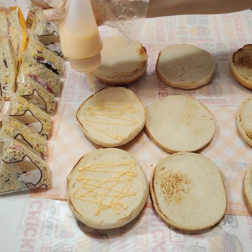Geheimsoße wird in einem Zickzack-Muster auf die Oberfläche der Burger-Brötchen gedrückt.