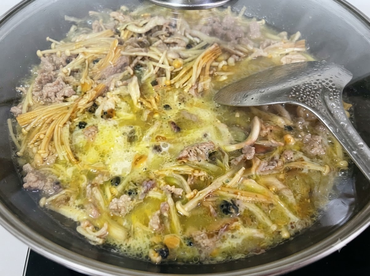 Flüssige Süßkartoffelstärkemischung wird aus einem Messbecher in den Wok gegossen.