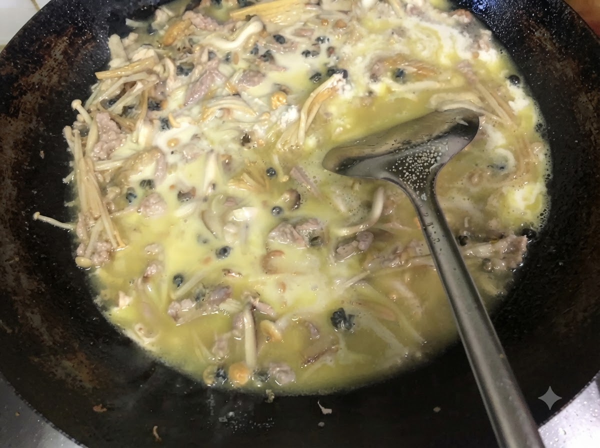 Frischer, gehackter grüner Schnittlauch wird mit einem Metallwender unter die dicke, gekochte Füllung im Wok gehoben.