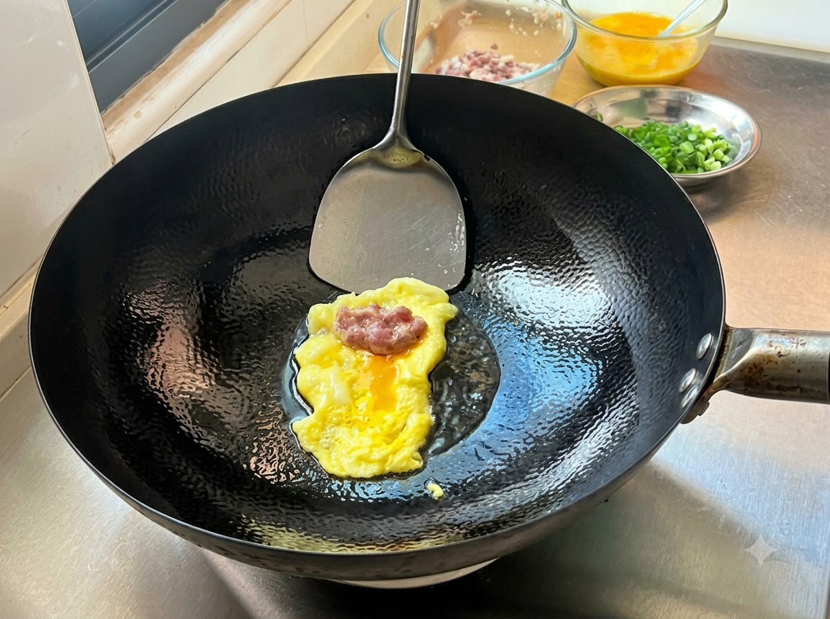 Ein Portion gewürztes Hackfleisch auf einem frisch gebackenen, dünnen Eierpfannkuchen in einem heißen Wok, bereit zum Falten.