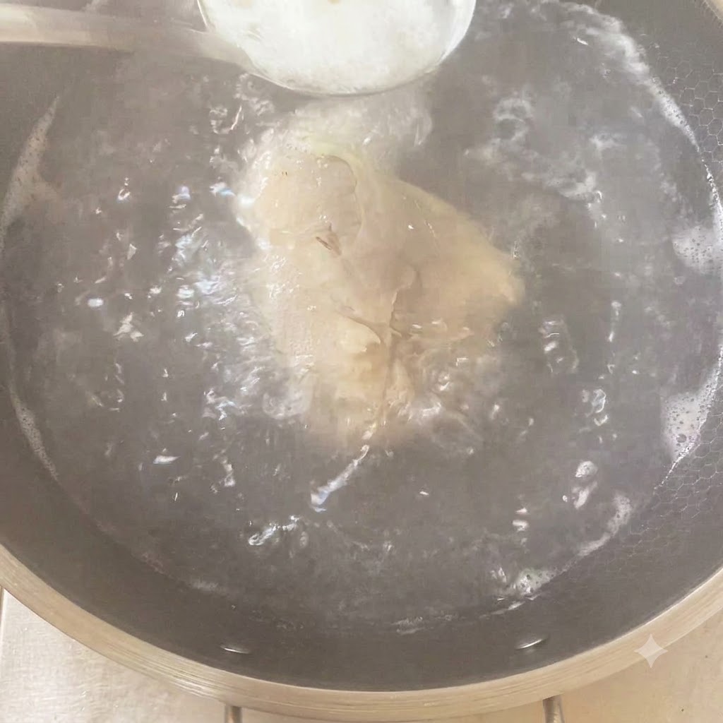 Ein Löffel Gewürze wird in einen kochenden Topf mit Hähnchen und Aromen gegeben.