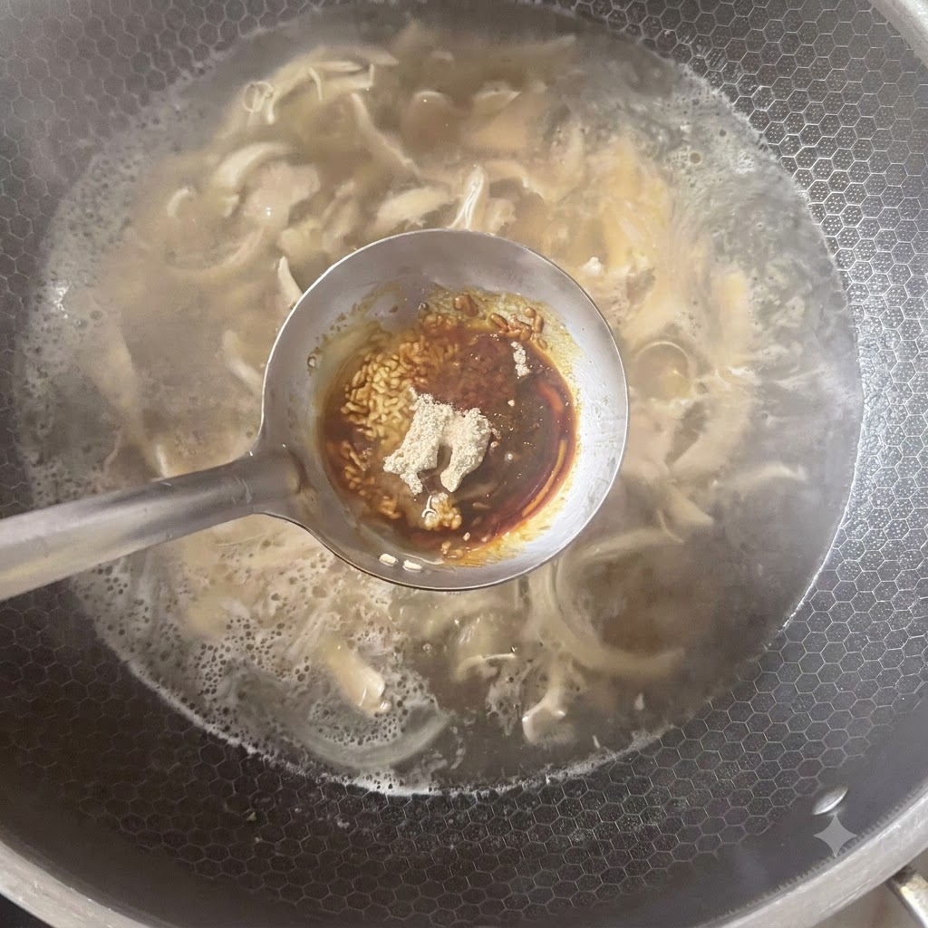 Eine Schöpfkelle mit verschiedenen Gewürzen, darunter weißer Pfeffer und Soßen, über einem köchelnden Suppentopf.