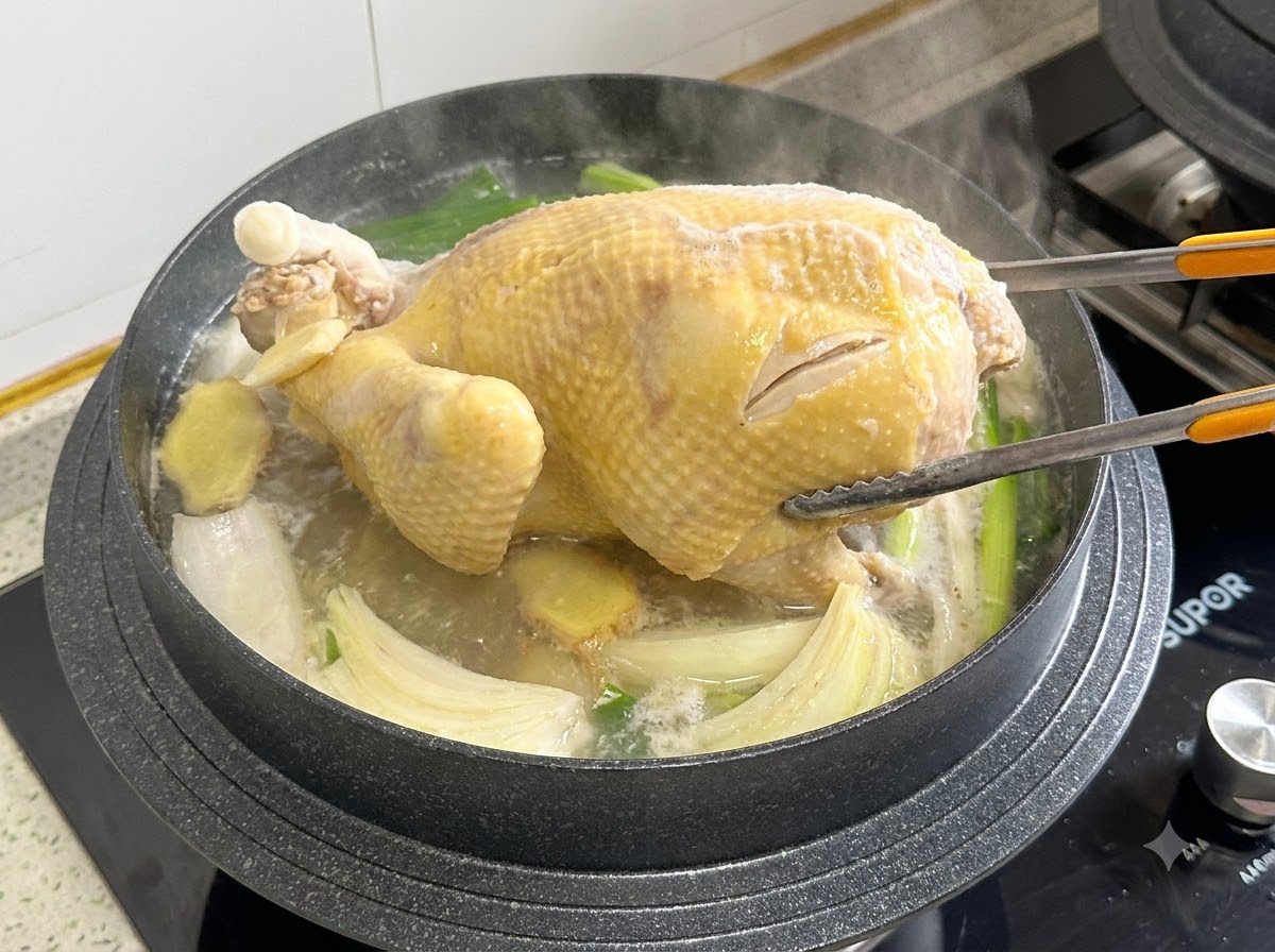 Kochzangen greifen und drehen ein ganzes Hähnchen in einem kochenden Topf mit Brühe.