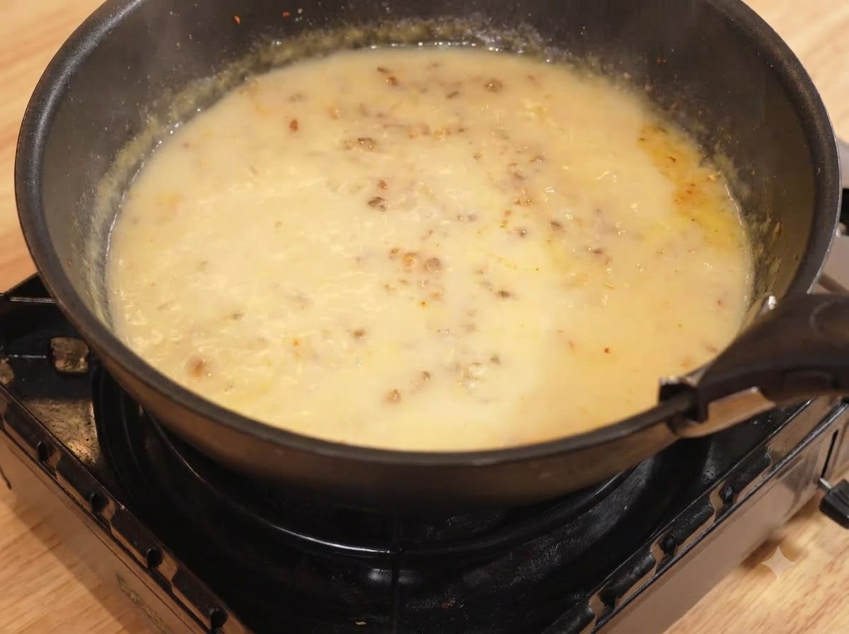 Wasser und Milch werden in die Pfanne mit der Currymischung gegossen und bei schwacher Hitze geköchelt.