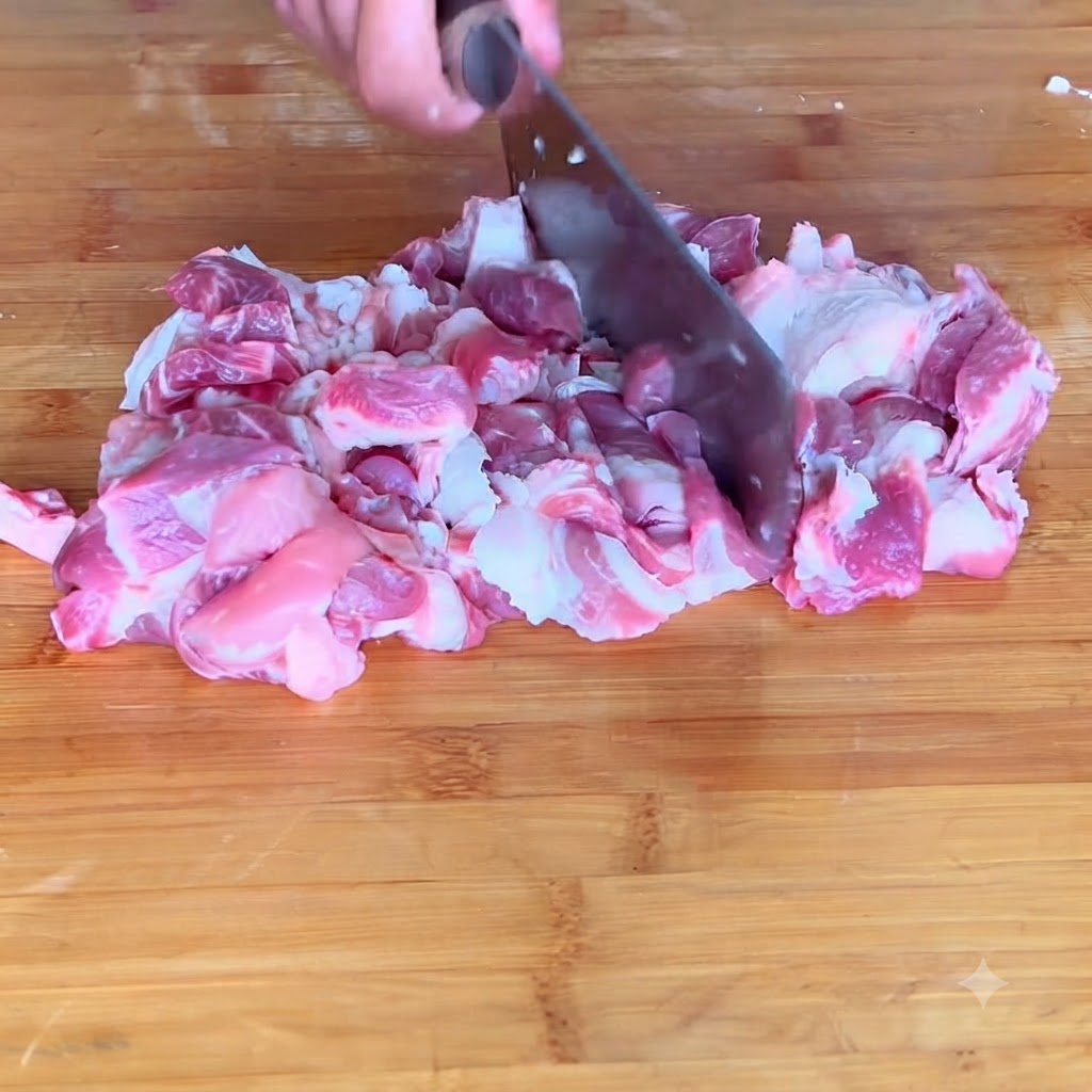 Nahaufnahme von Schweinefleisch, das auf einem Schneidebrett zu einer feinen Fleischpaste gehackt wird.