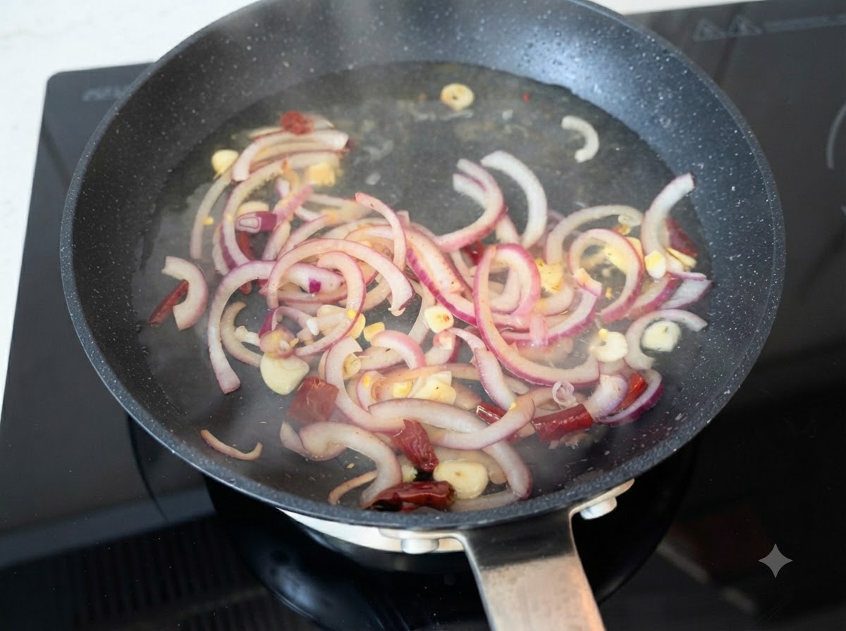 Heißes Wasser wird über sautierte rote Zwiebelscheiben, Knoblauch und Chilischoten in einer Pfanne gegossen.