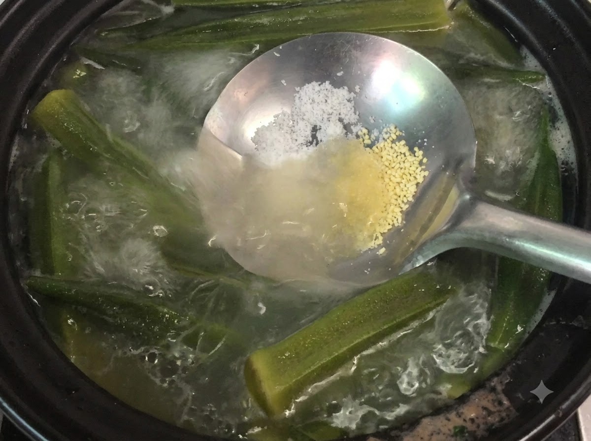 Eine Kelle hält Salz und Hühnerpulver über einen köchelnden Topf mit Okra- und Knochensuppecite: 1.
