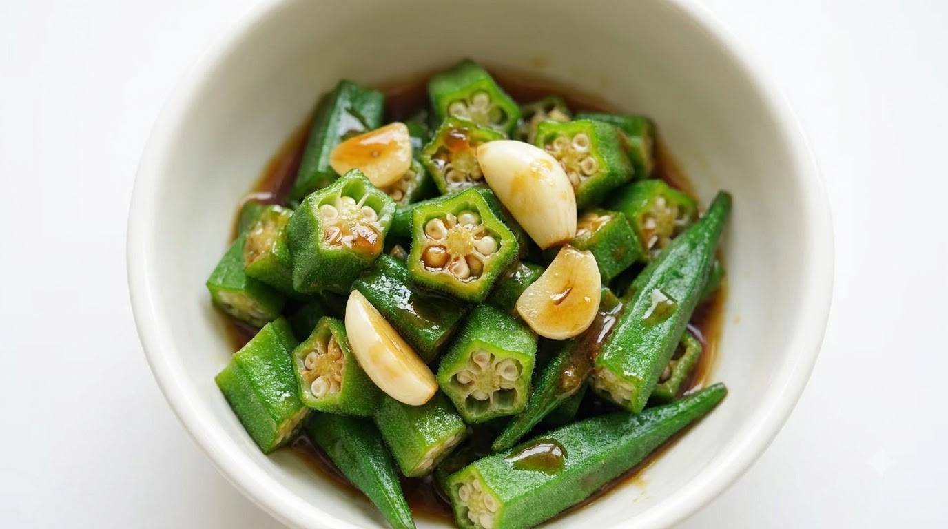 Eine Schüssel mit geschnittenem, grünem Okra, garniert mit Knoblauch und einer reichhaltigen, herzhaften braunen Sauce.