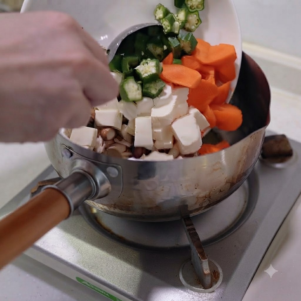 Gehacktes Gemüse und Tofu werden von einem weißen Teller in einen Edelstahltopf gegeben.