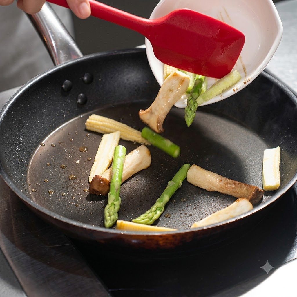 Spargel und Baby-Mais werden aus einer weißen Schale in die Bratpfanne mit den Pilzen gegeben.