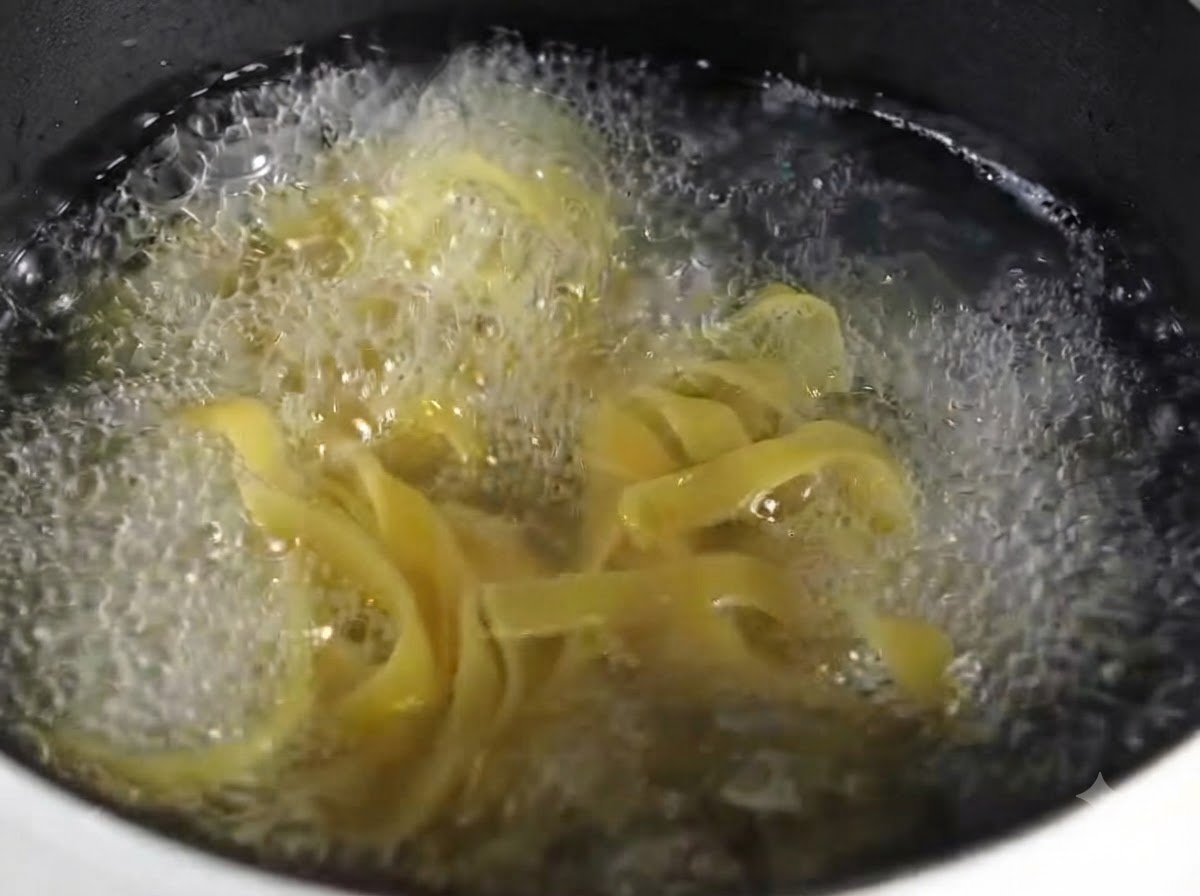 Nahaufnahme von gekochten Fettuccine-Nudeln, ordentlich auf einem runden grauen Teller angerichtet.