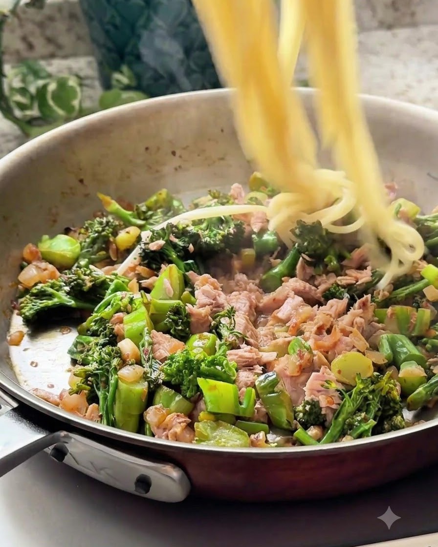 Gekochte Spaghetti werden in die Pfanne mit der Thunfisch-Gemüse-Mischung gegeben.