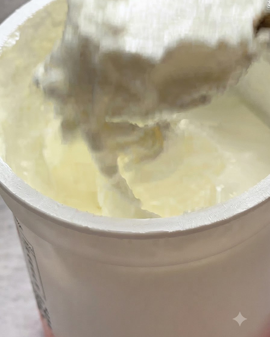 Ein Löffel ungesüßter Joghurt wird in einer Pfanne auf die Pasta gegeben.