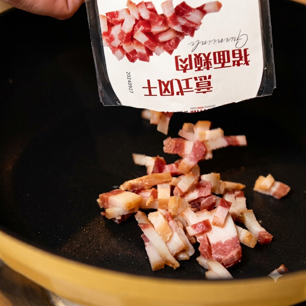 Stücke von gepökeltem Schweinebäckchen fallen aus einer Verpackung in eine erhitzte schwarze Bratpfanne.