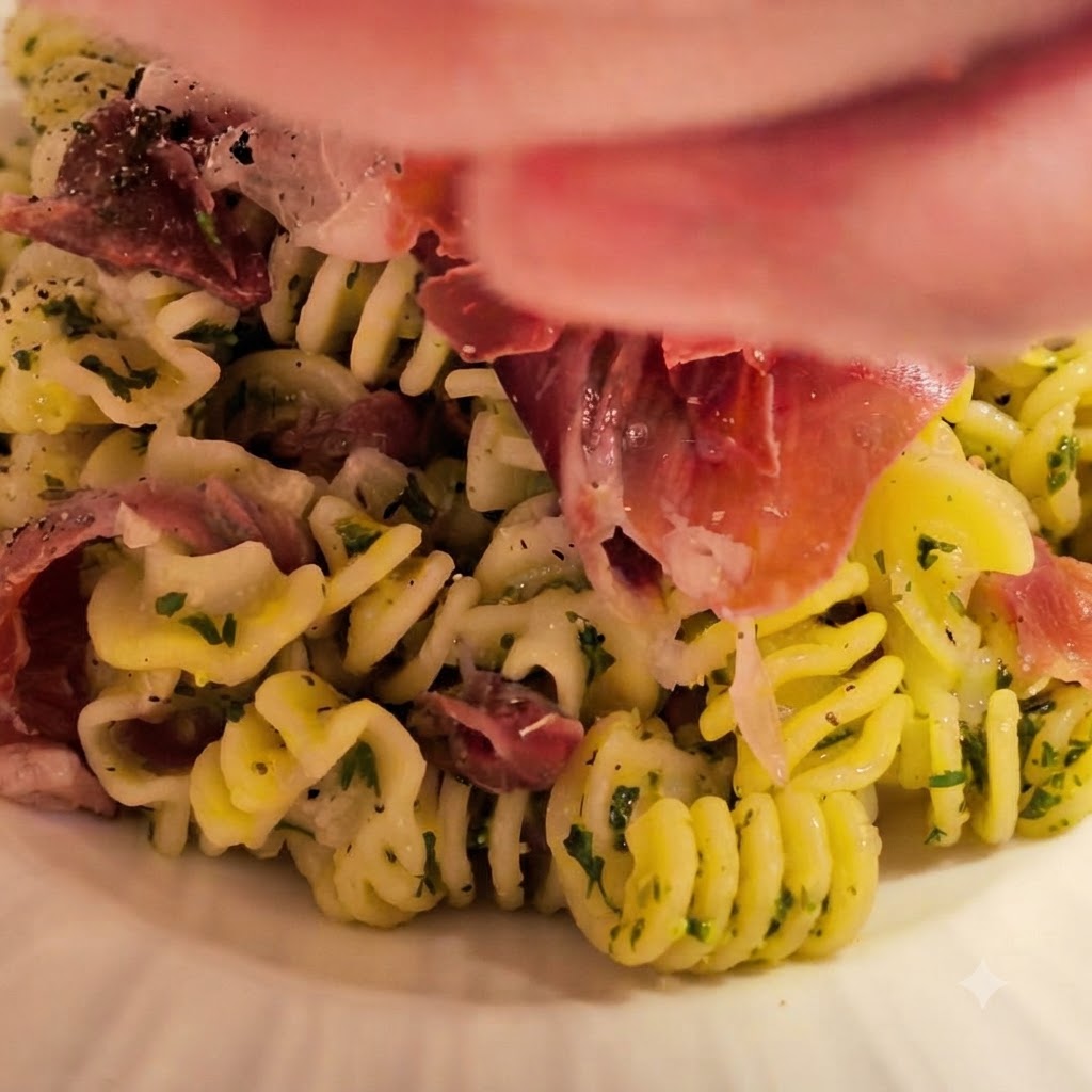 Frisch gekochte Spiralnudeln werden in die Schüssel mit der zubereiteten Butter-Knoblauch-Soße gegeben, garniert mit frischen Kräutern und Schinken.