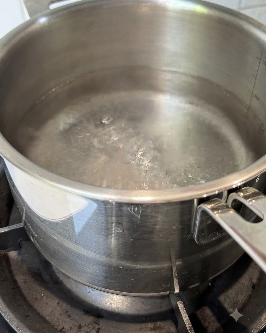 Trockene Spaghettinudeln werden in einen Topf mit kochendem Wasser gegeben.