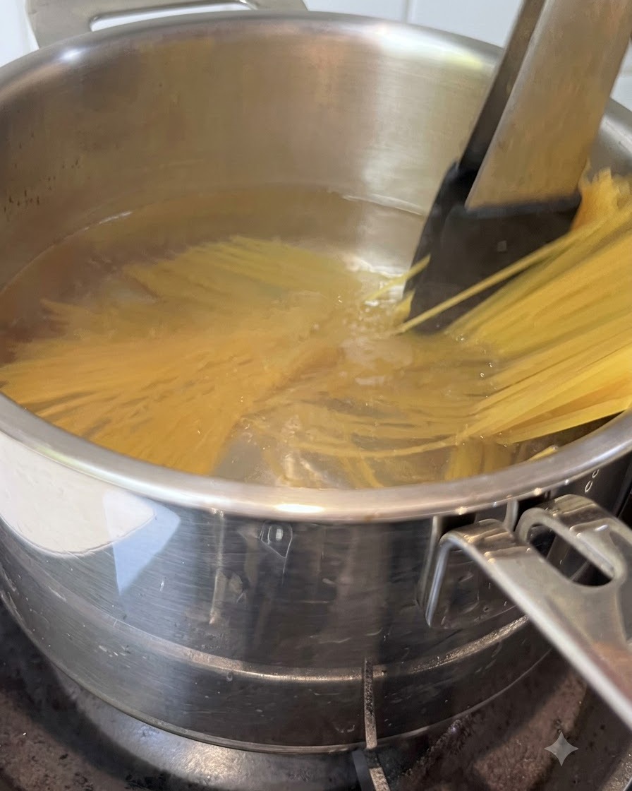 Spaghetti werden mit einer Zange in einem Topf mit kochendem Wasser umgerührt.