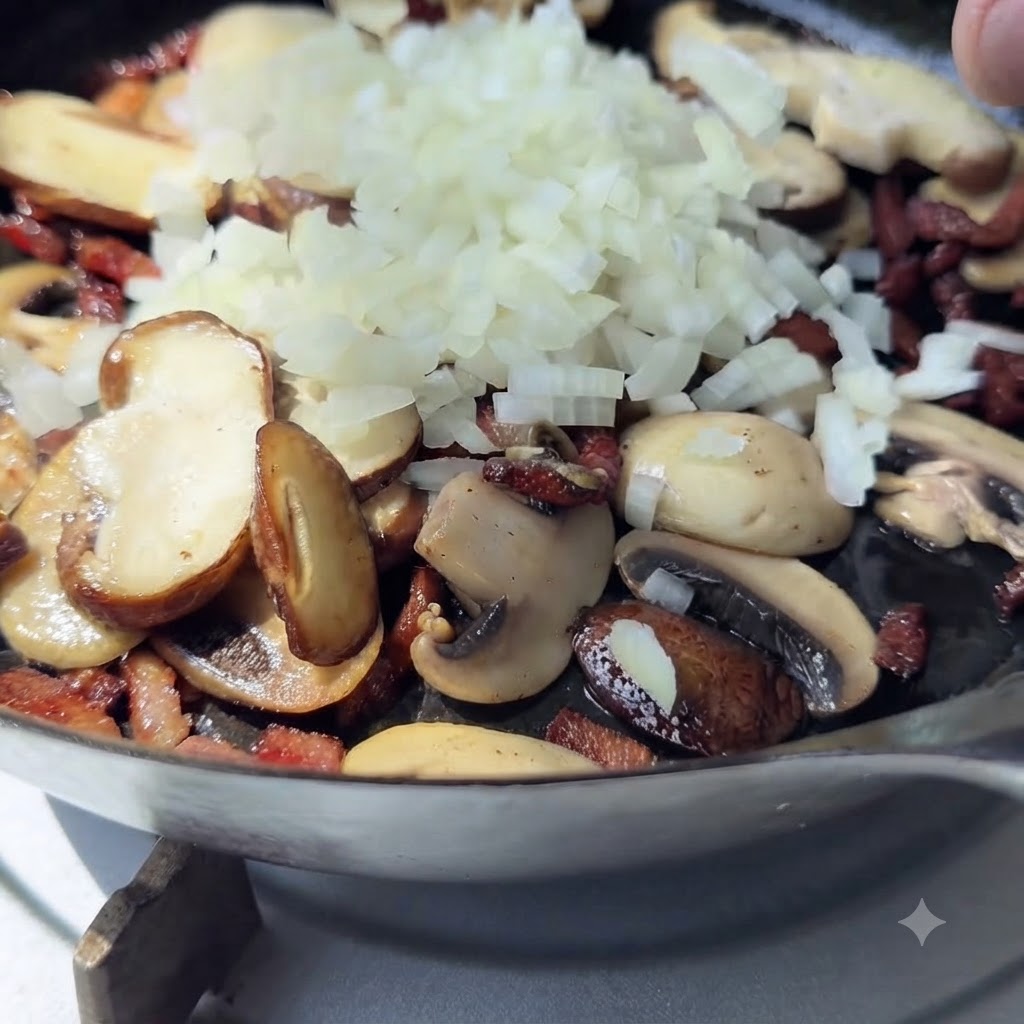 Ein Haufen frisch gewürfelter weißer Zwiebeln liegt auf gekochten Pilzen und Speck in einer Pfanne.