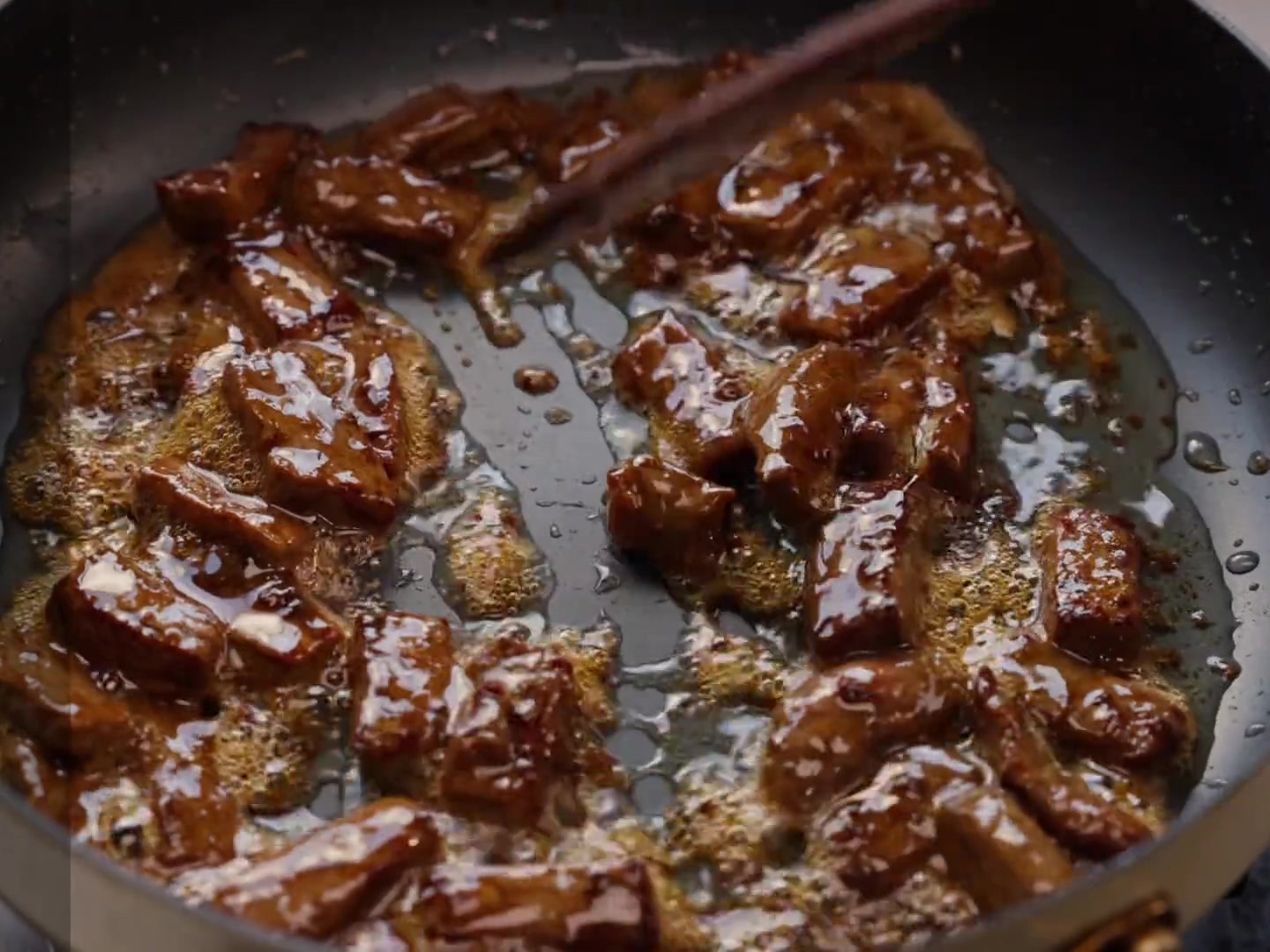 Geschnittene Paprika und Zwiebeln werden in eine Pfanne mit braunen Steakstücken gemischt.