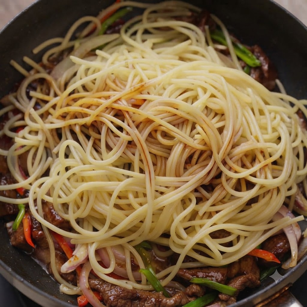 Saucen werden über Spaghetti-Nudeln und Rindfleisch in einer Kochpfanne geträufelt.