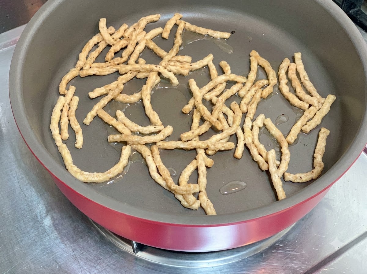 Pflanzliche Protein-Streifen werden in einer heißen Pfanne mit etwas Öl angebraten.