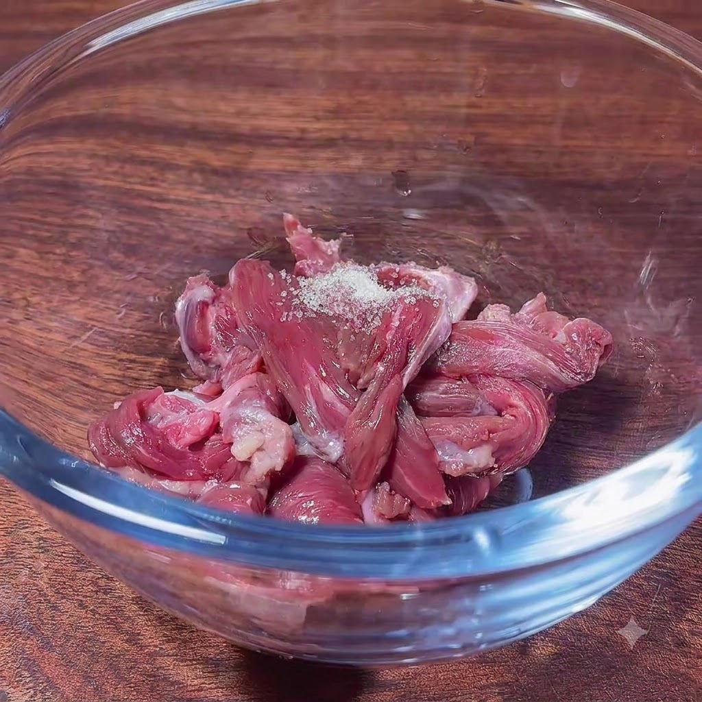 Rohe Rindfleischscheiben in einer Glasschüssel mit Zucker, bereit zum Vermengen mit den Marinadenzutaten.