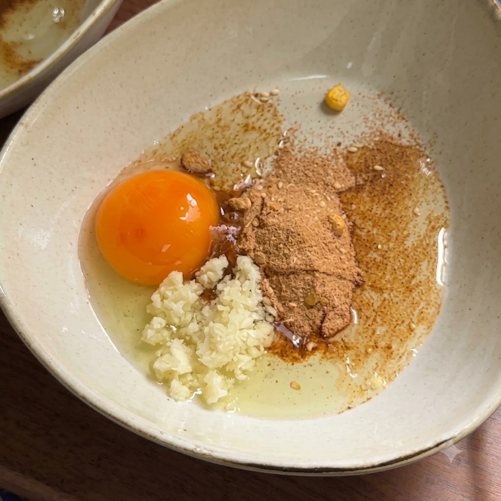 Mayonnaise wird in eine Schüssel mit rohem Eigelb, Knoblauch und Gewürzpulver gedrückt.