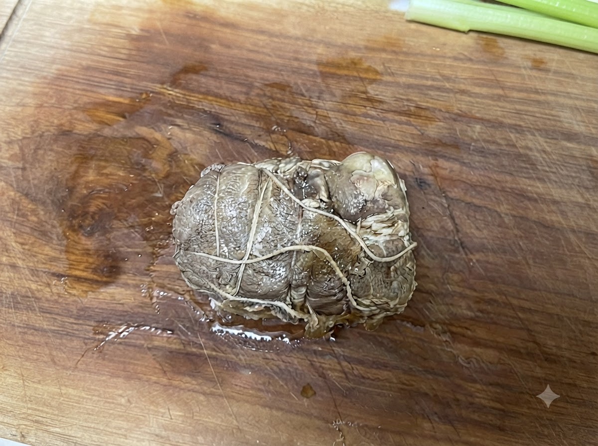 Gebundenes, rollenförmiges Chashu-Schweinefleisch auf einem Holzschneidebrett vor dem Aufschneiden.