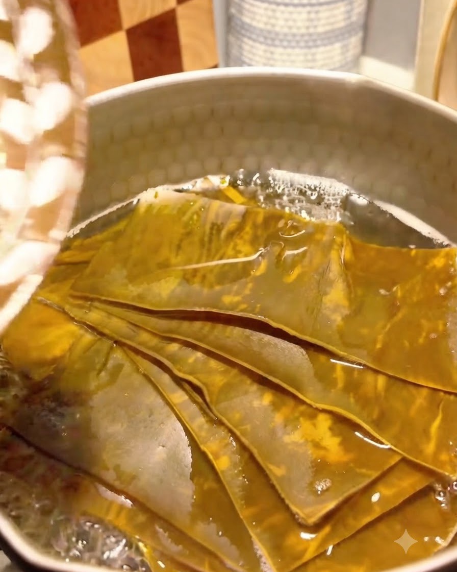 Bonitoflocken werden in die köchelnde Kelp-Brühe in einem Topf gegeben.