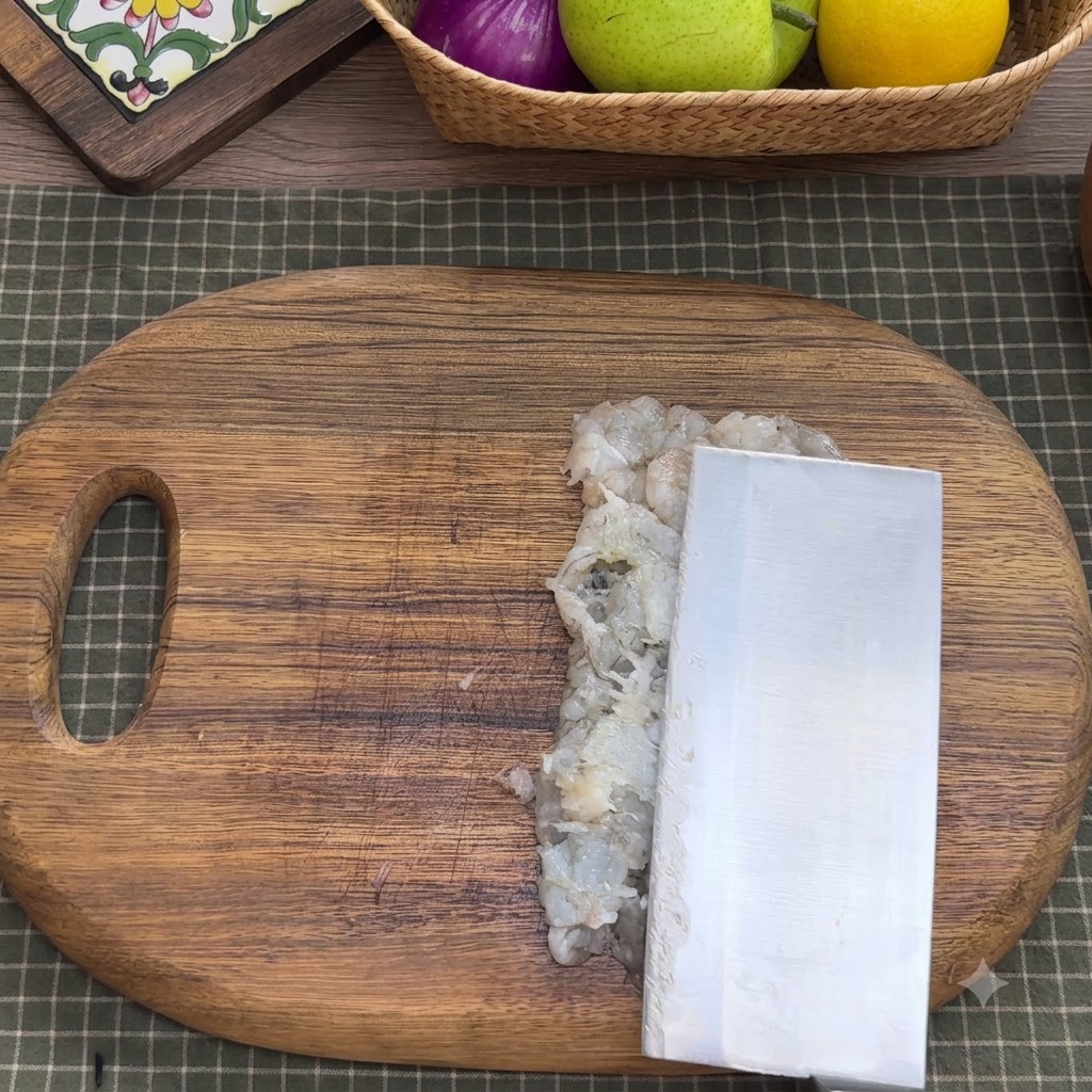 Gehacktes Garnelenfleisch in einer Rührschüssel aus Metall mit Gewürzen, Eiweiß, Stärke und Wasser.