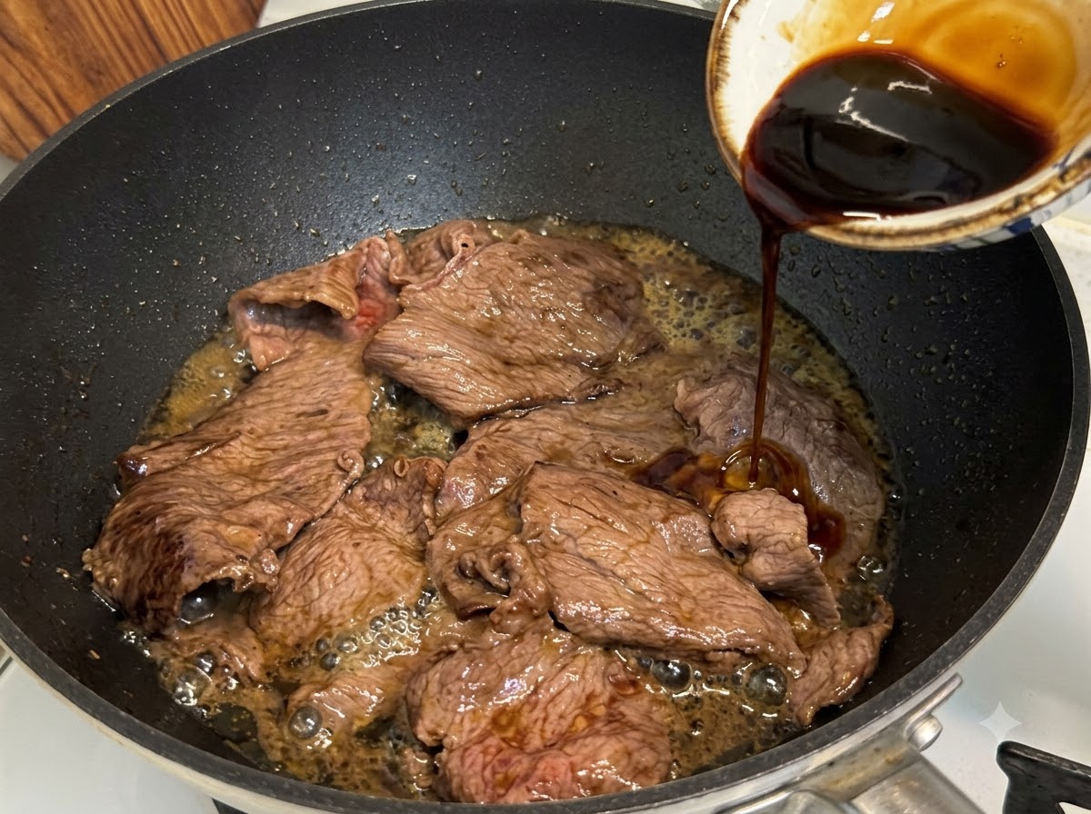 Teriyaki-Sauce wird in eine Pfanne über geschnittenes fettes Rindfleisch gegossen, um zu köcheln und einzukochen.