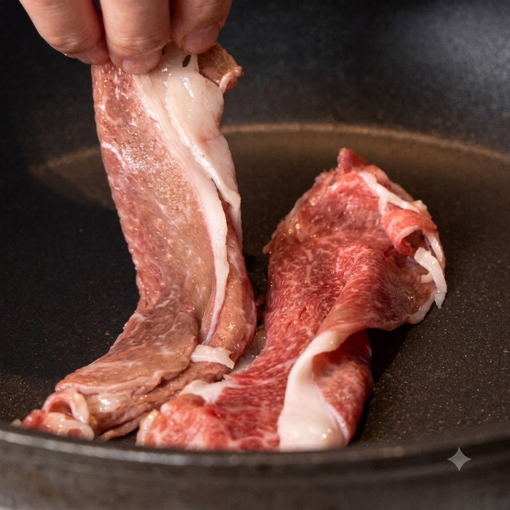 In Scheiben geschnittenes Wagyu-Rindfleisch wird in eine trockene, erhitzte beschichtete Pfanne gelegt.