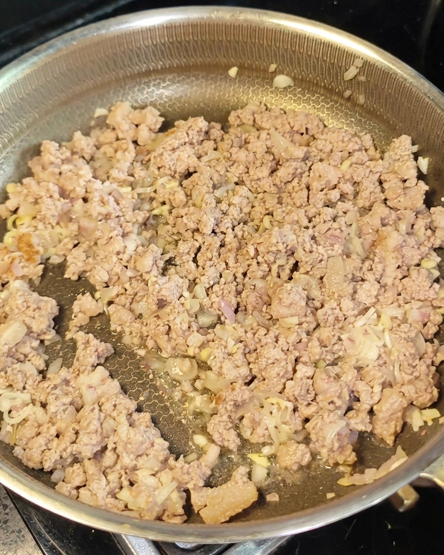 Angebratenes Hackfleisch und Aromen in einer Pfanne, während rote Miso-Paste eingearbeitet wird.