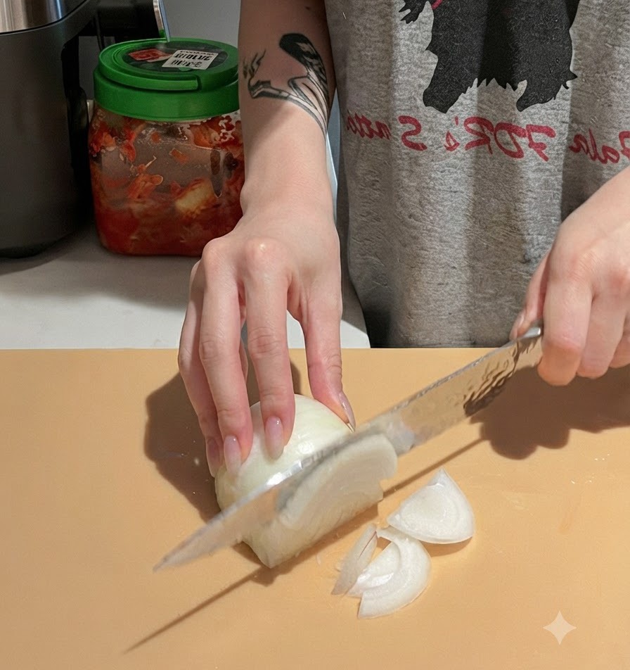 Hände schneiden sorgfältig eine weiße Zwiebel mit einem Kochmesser auf einem Schneidebrett.