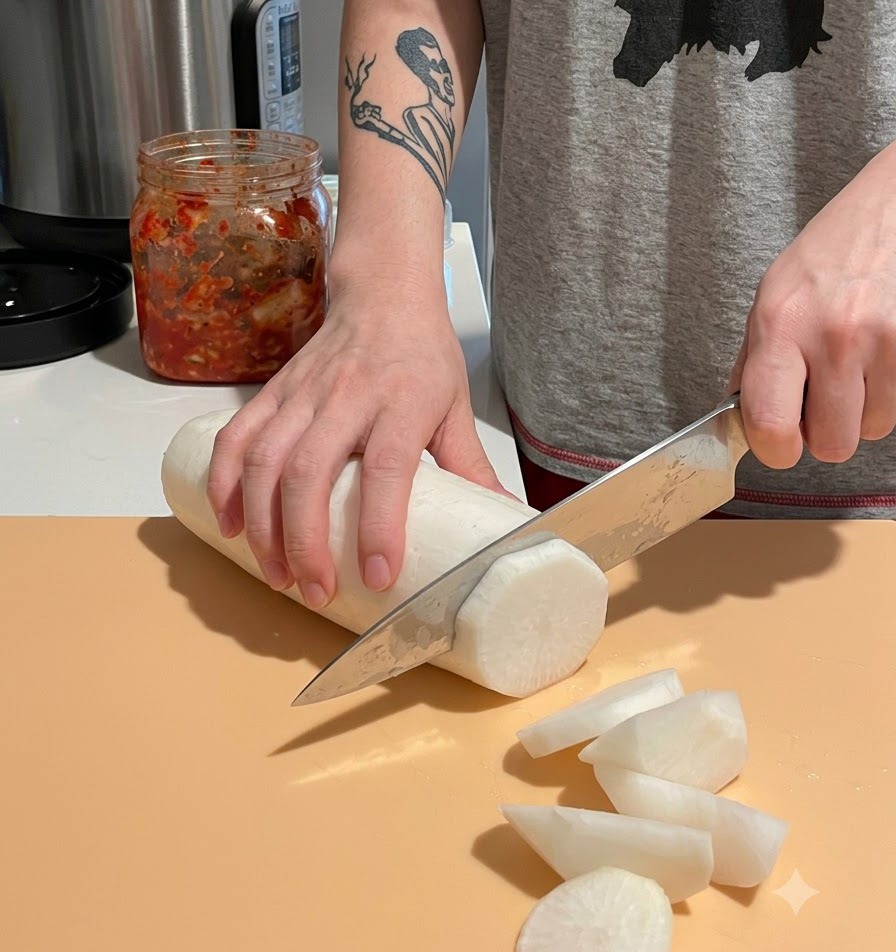 Ein geschälter weißer Daikon-Rettich wird auf einem Schneidebrett in große, dicke Stücke geschnitten.