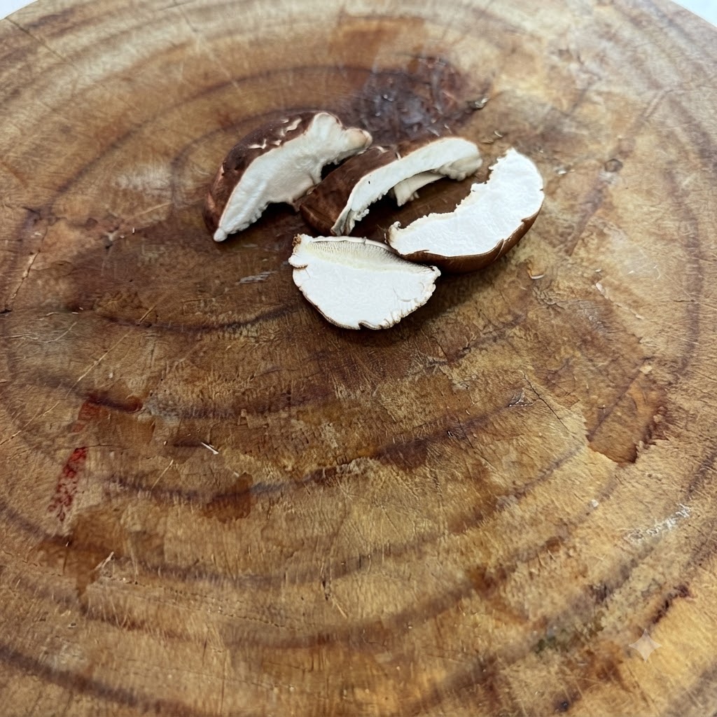 Dünn geschnittene frische Shiitake-Pilze liegen auf einem Holzschneidebrett.