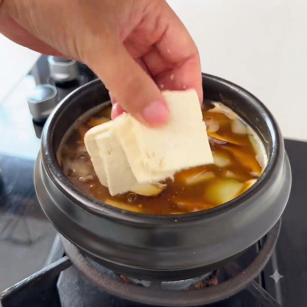 Tofustücke werden in die Suppe mit Zucchinischeiben und Enoki-Pilzen gegeben.