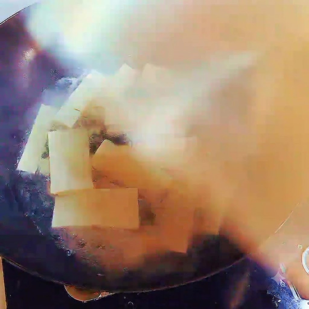 Ein Wok gefüllt mit kochender Suppe und Tofustreifen, sicher mit einem Deckel abgedeckt.