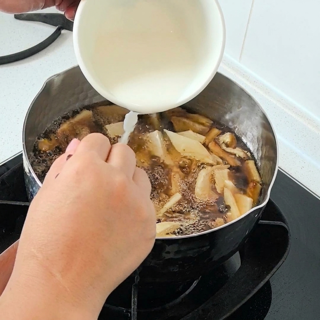 Wasserstärke wird aus einer weißen Schüssel in einen blubbernden Suppentopf gegossen.
