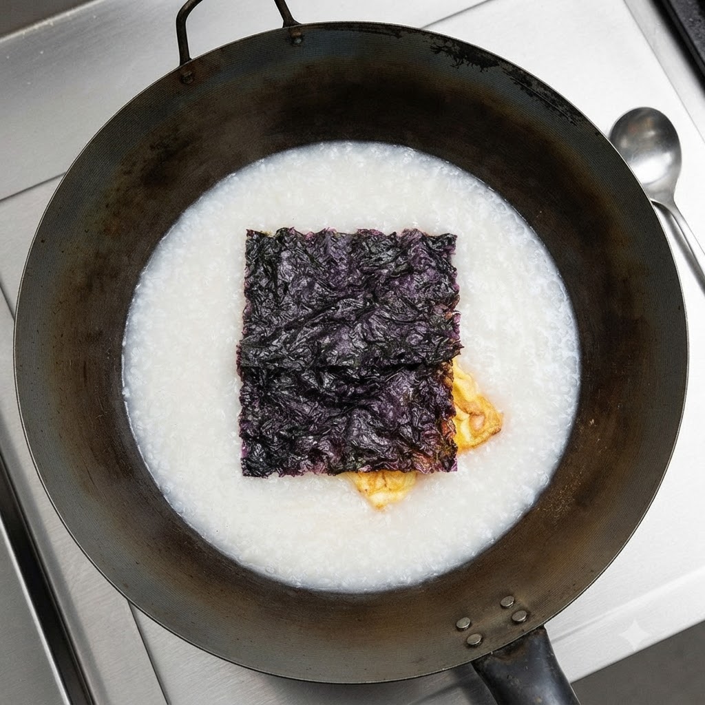 Getrockneter Seetang schwimmt oben auf der weißen Suppe im Wok.