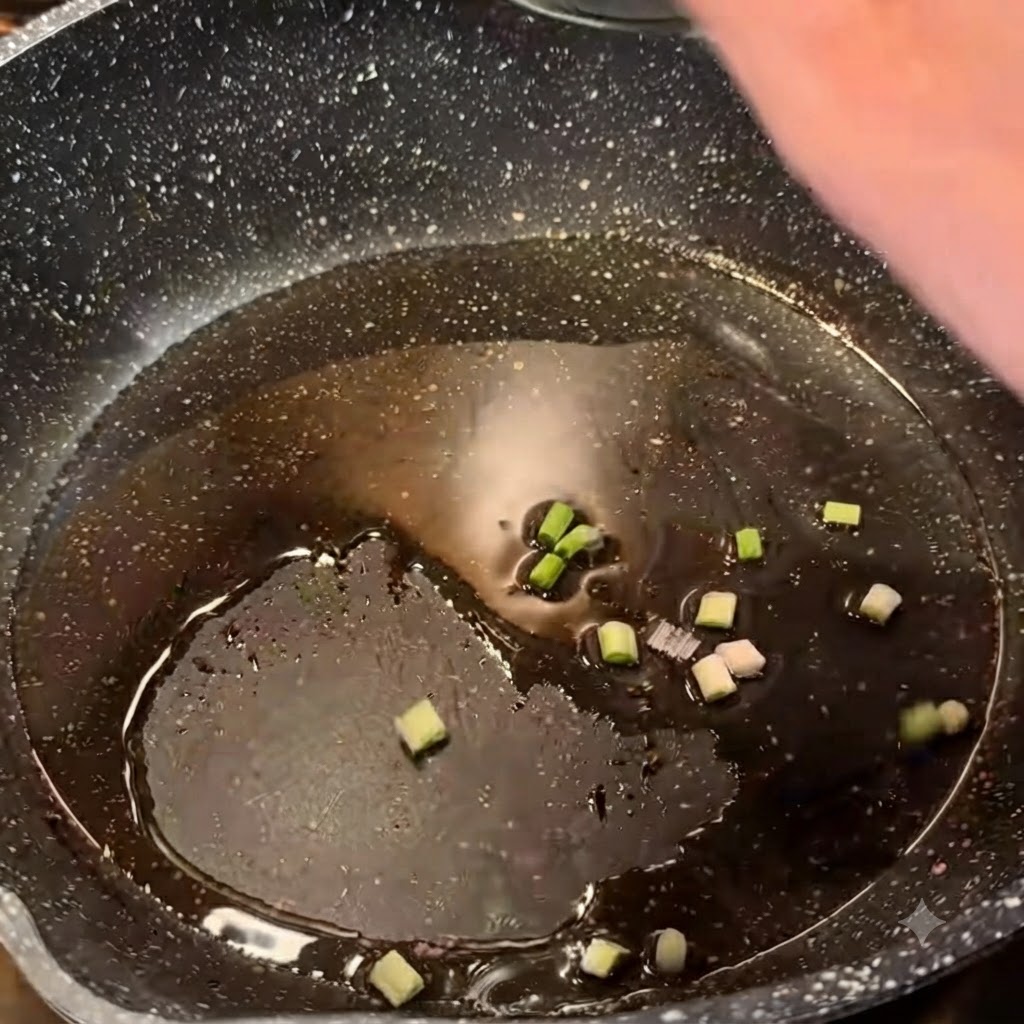 Gehackte Frühlingszwiebeln brutzeln in heißen Öl in einer dunklen Bratpfanne.