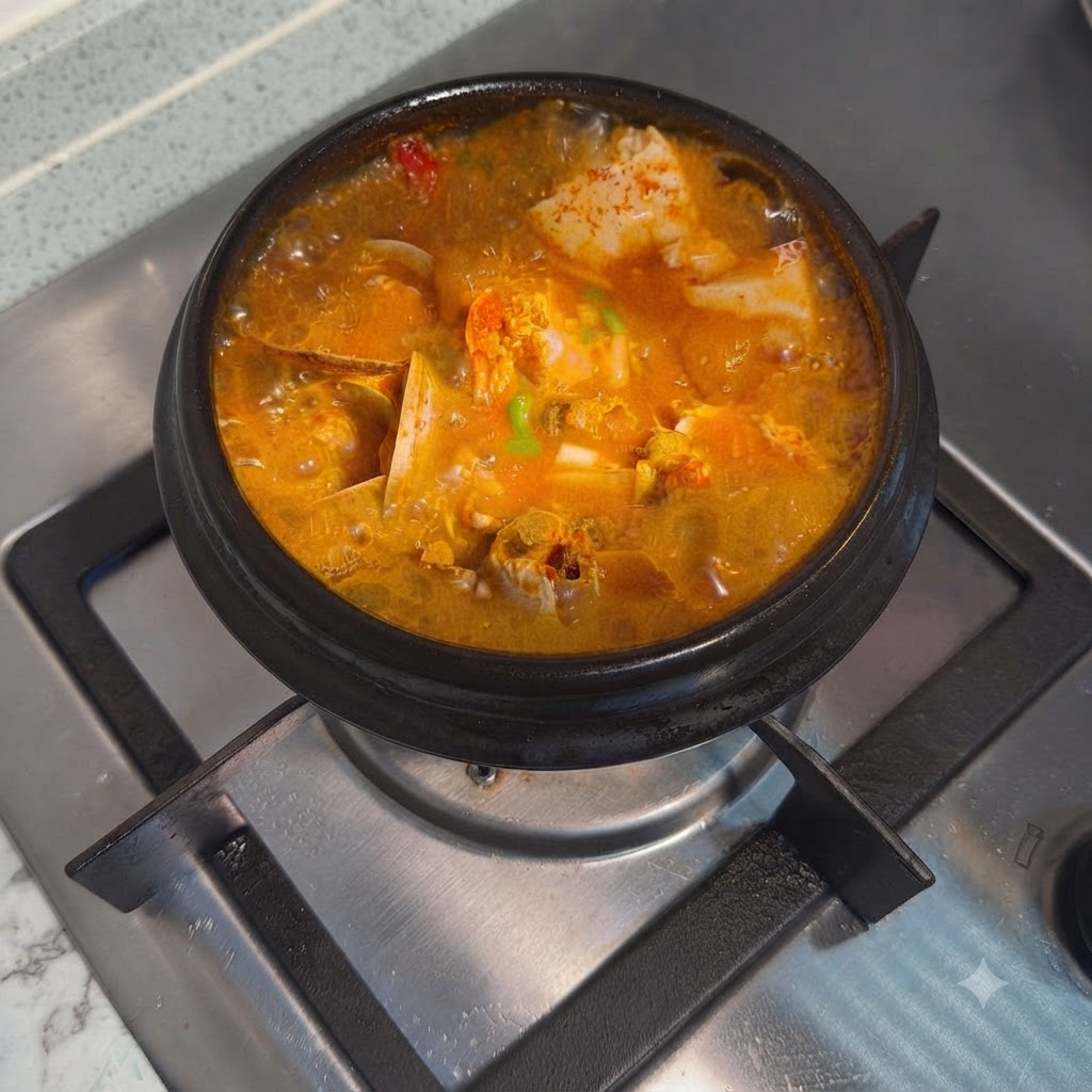 Der fertige koreanische pikante Seidentofu-Eintopf, garniert mit gehackten Frühlingszwiebeln in einem heißen Steintopf.