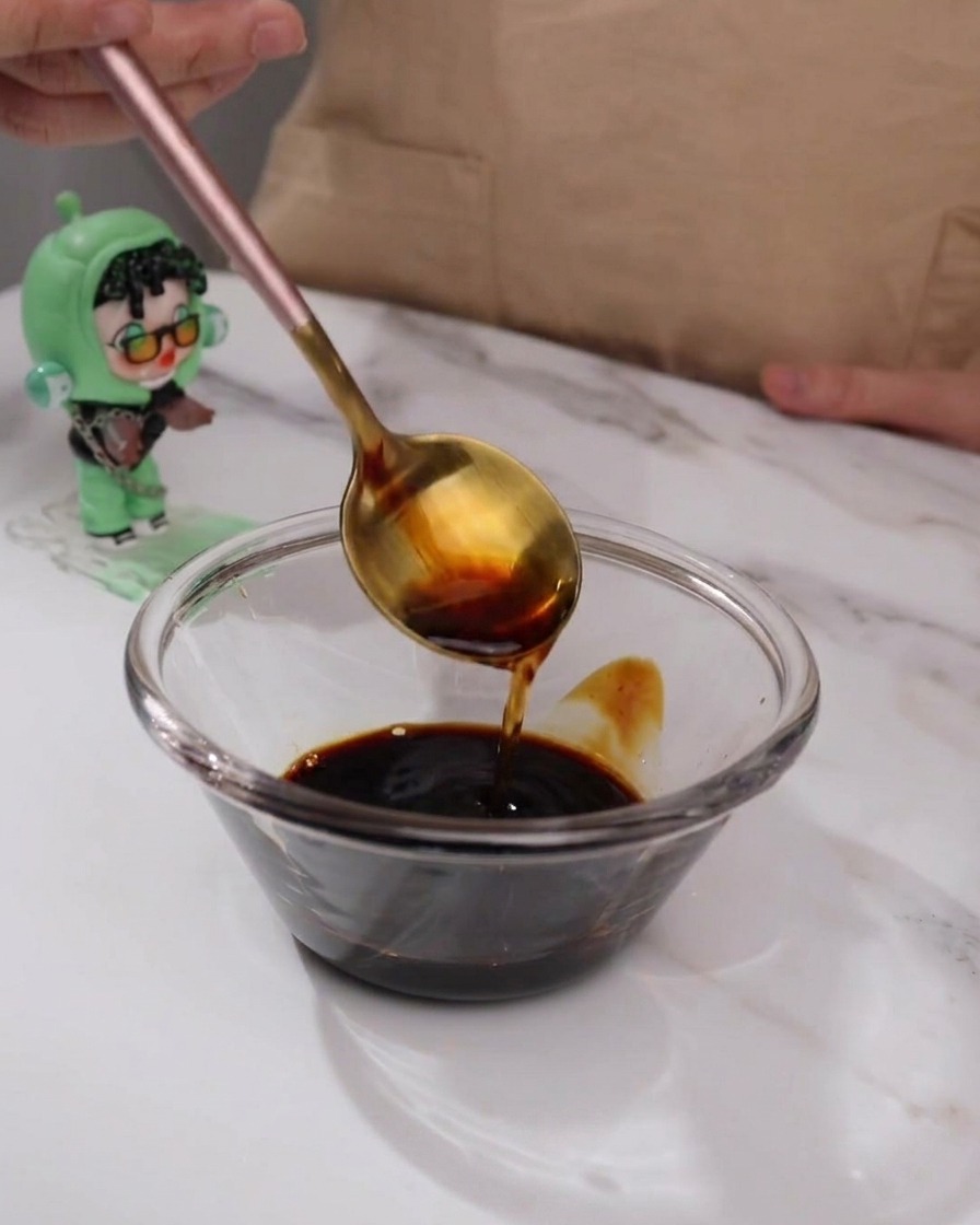 Teriyaki-Soßen-Zutaten werden in einer kleinen Glasschüssel mit einem Löffel vermischt.